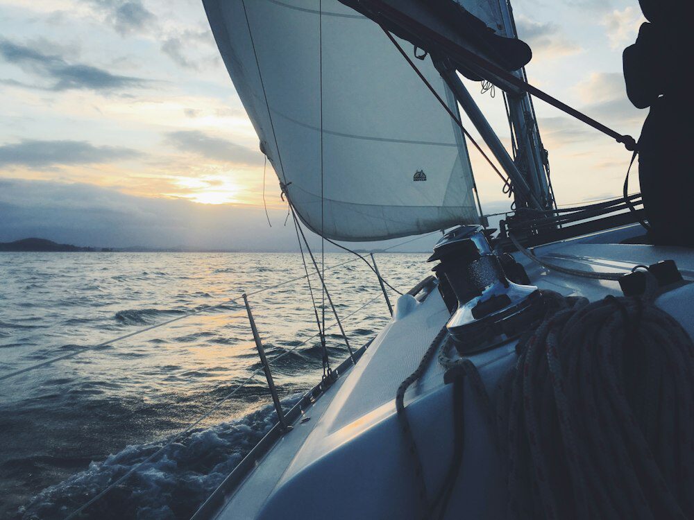 A serene white sailing boat gliding on the water, epitomizing the tranquility and beauty of sailing adventures