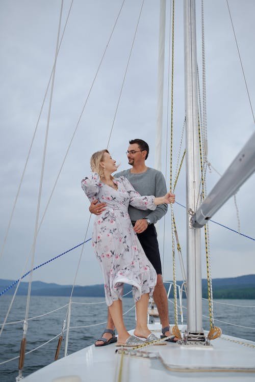 A joyous couple embracing on a sailboat, surrounded by the vast sea, capturing the essence of love and blissful moments.