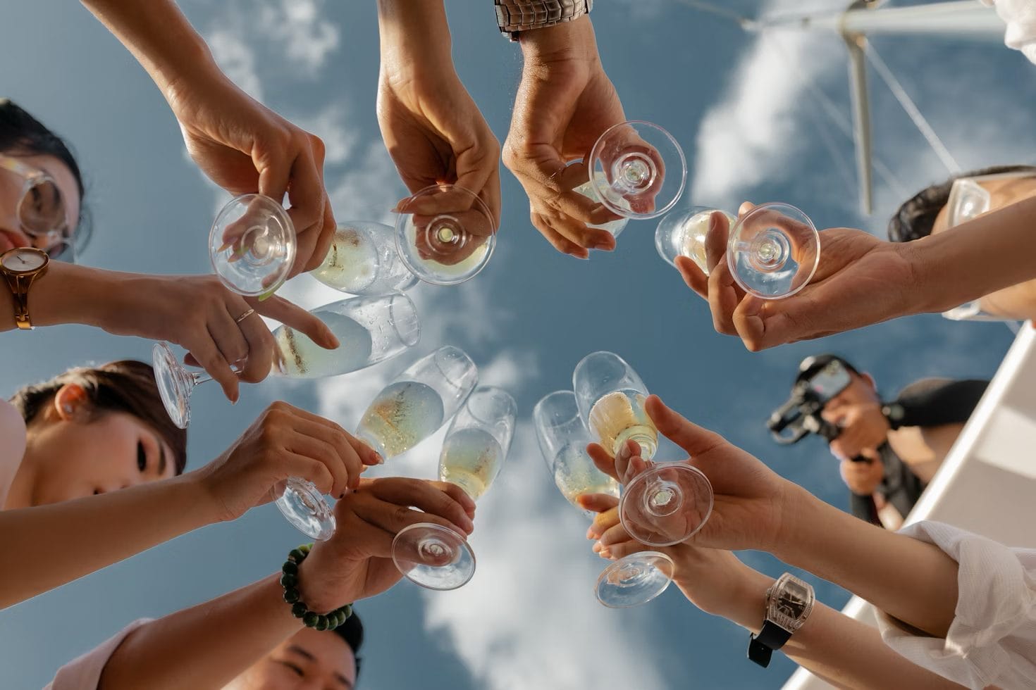 family and friends holding clear glasses filled with champagne during a yacht party